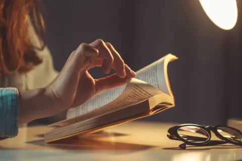 woman-reading-book-evening-home-close-up