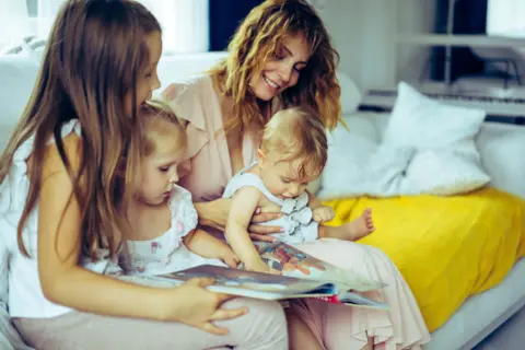 mother-with-three-children-reading-book-homely-atmosphere