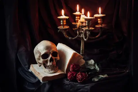 human-skull-book-with-antique-candlestick-still-life-1