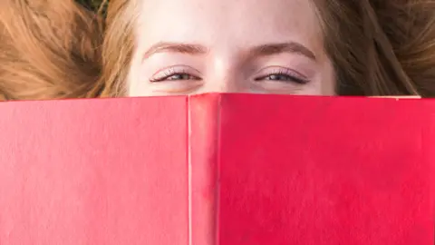 beautiful-girl-covering-her-mouth-with-red-book