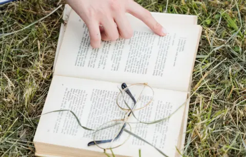 hand-pointing-open-book-grass-1