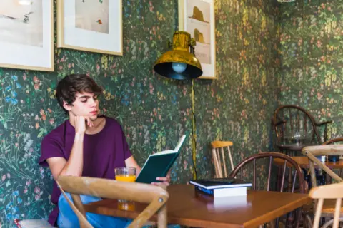 handsome-teenager-reading-cafe