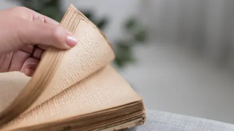 close-up-hand-holding-old-braille-book
