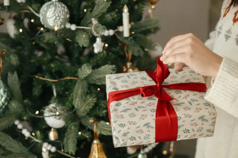1-woman-hands-opening-stylish-christmas-gift-with-red-ribbon-close-up-modern-decorated-vintage-tree-scandinavian-room-merry-christmas-happy-holidays