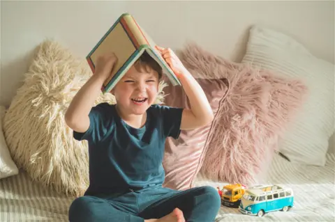 little-boy-sits-bed-with-book
