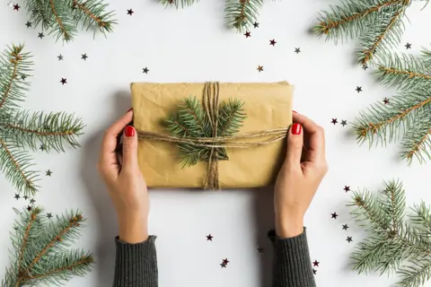 2-woman-hand-holding-gift-box-christmas-decoration-composition-spruce-fir-brunch